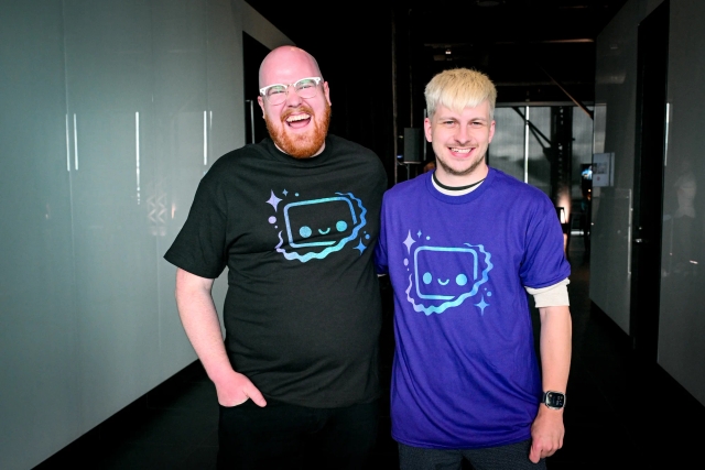 Nate, core contributor, and Alex, maintainer, posing together with their Houston printed t-shirts. One in black and the other purple.