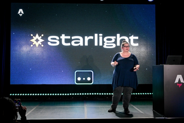 Sarah Rainsberger speaking on stage next to an Astro-branded podium. The Starlight logo is displayed alongside Houston behind her.