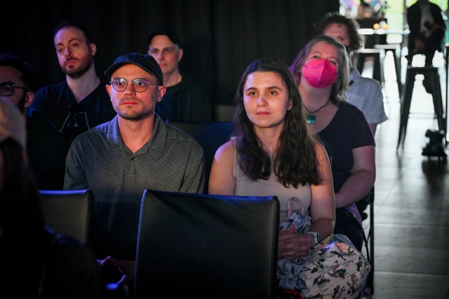 Audience members listening to Sarah Rainsberger speaking on stage.