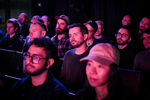 Audience members listening to Sarah Rainsberger speaking on stage.