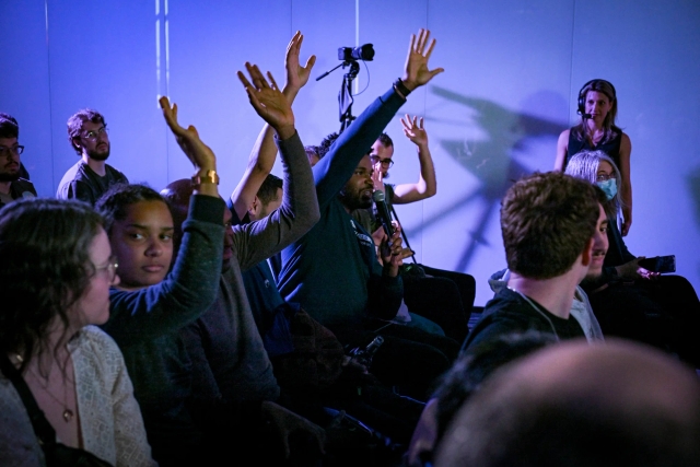 Audience members holding their hands up to be chosen for Q&A.