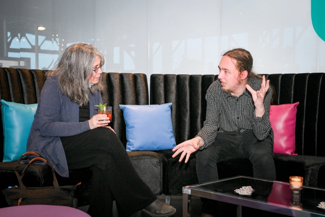 Reuben, of Astro, sitting it the Houston lounge chatting with a guest as she holds her drink.