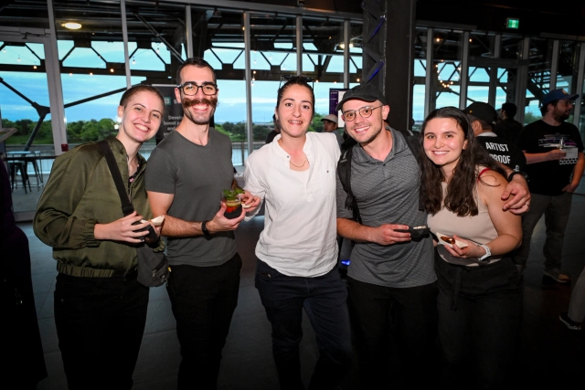 Guests pose for a group photo while holding their food and drink.