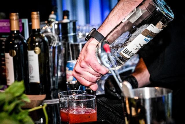 Closeup of a bartender pouring a pink drink.